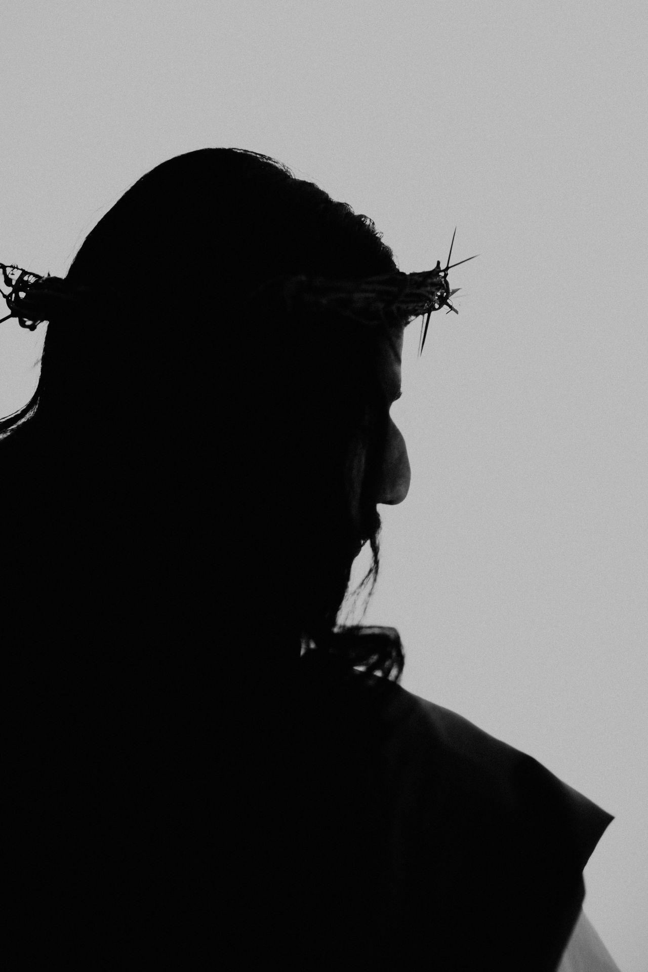 Black-and-white silhouette of a figure wearing a crown of thorns